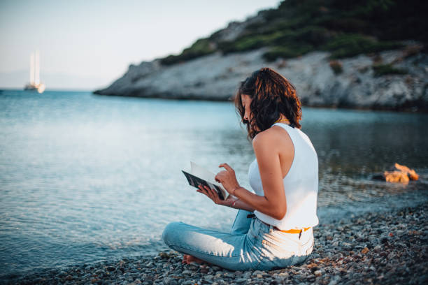 istock Woman Reading Book and Relaxing at the Beach 1257428544