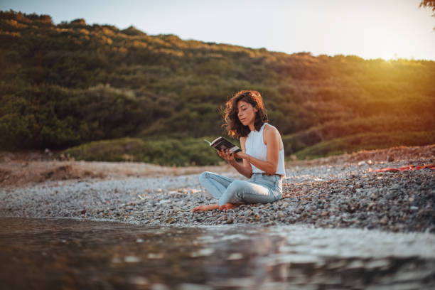 woman reading book and relaxing at the beach - reading outside imagens e fotografias de stock