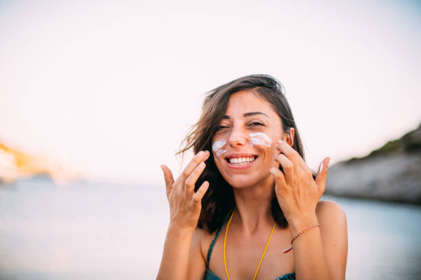 istock Woman Protecting Her Face With Sunscreen at the Beach 1257429594