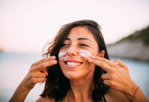 istock Freckled Woman Protecting Her Face With Sunscreen at the Beach 1257429628