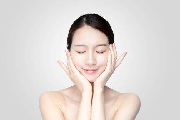 jovem asiática tocando rosto com expressão relaxada - asian ethnicity asia massaging spa treatment - fotografias e filmes do acervo
