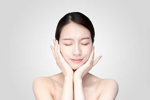 Mujer joven asiática tocando la cara con expresión relajada photo
