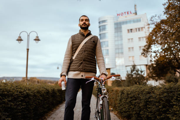istock Young man with a bicycle carrying coffee cup in the park 1257431941