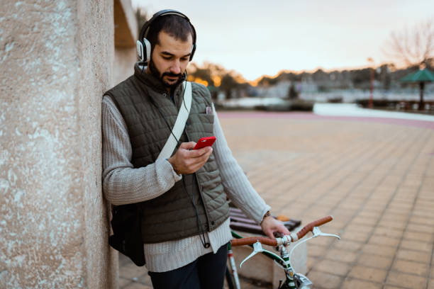 istock Young man using headphones and smartphone in the city park 1257432013