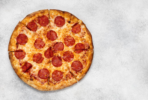 istock Pepperoni pizza on white concrete background. Top view with copy space. Tasty sliced pepperoni pizza 1257433176