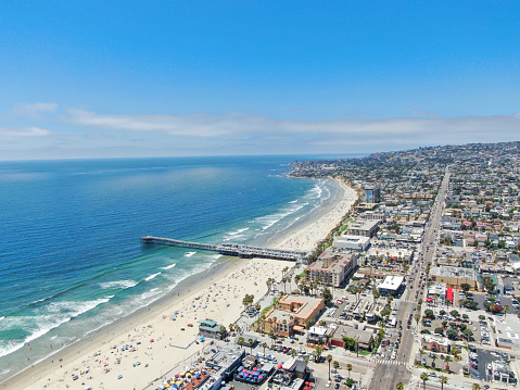 Aerial view of people at the beach near the pier with during blue summer day. Pacific Beach in San Diego, California