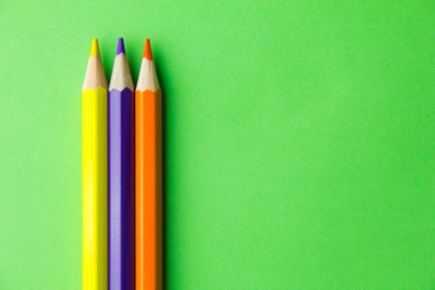 istock Yellow, purple and orange pencils on green background. Copy space for text. 1257436028