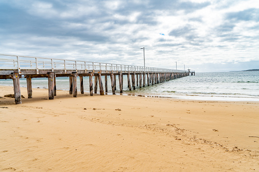 A wooden pier with a gazebo and a thatched roof in the sea, a sunny day fills this spot with tranquility and warmth. Landscape video