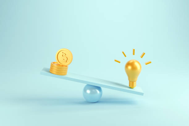 istock Idea vs coins on scales, Weights with light bulb and coins. 1257437364