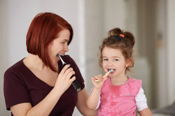 Photo of Mother and daughter brushing their teeth