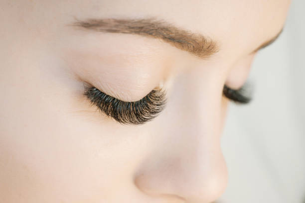 procedimento de extensão de cílios. vista de perto de olhos de mulheres bonitas com cílios longos. cílios alongamento para a menina em um salão de beleza. conceito de beleza. - cílios postiços - fotografias e filmes do acervo