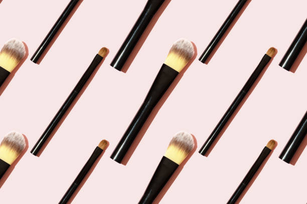 istock A pattern of black makeup brushes. Modern bright decorative background. Women's accessories on a pink background. Professional makeup artist's tool for applying eyeshadow and foundation 1257439534