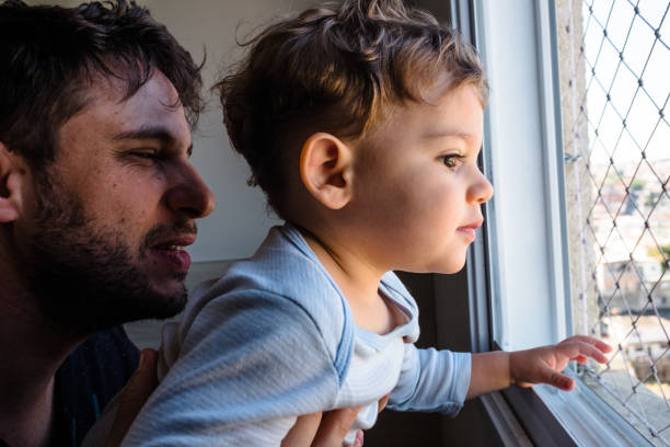 istock Father and Son Looking Through the Window 1257440188