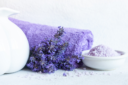 Lavender flowers,  aromatic sea salt and towels. Concept for spa, beauty and health salon, cosmetics store. Close up photo on white wooden background.