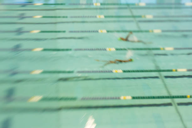 Swimmers Racing in Pool Abstract Motion Blur Swim Swimmers swim backstroke at a meet. Abstract motion blur. swimming pool lane ropes stock pictures, royalty-free photos & images