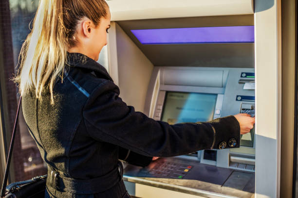 istock Young woman taking money from ATM 1257447107