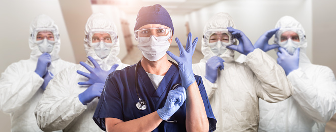 Team of Female and Male Doctors or Nurses Wearing Personal Protective Equipment In Hospital Hallway.