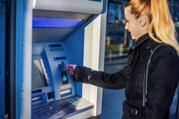 istock Pretty young woman is using ATM 1257447447