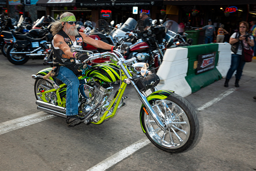 Sturgis, South Dakota - August 9, 2014: A byker riding his chopper motorcycle during the annual Sturgis Motorcycle rally in the main street of the city of Sturgis.