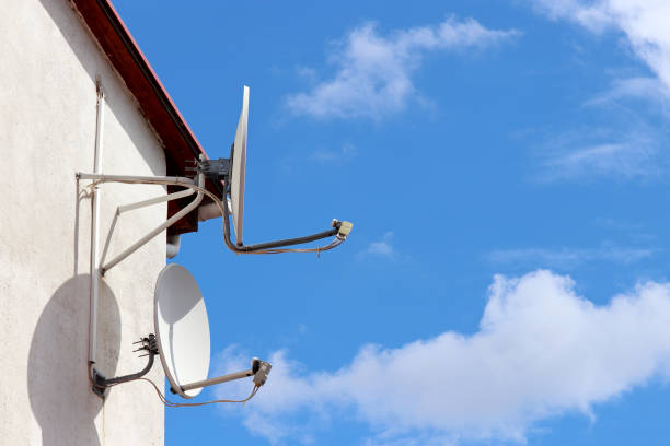 istock Satellite antennas on house wall on background of blue sky with white clouds 1257452111