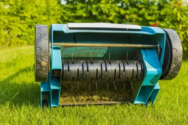 Photo of Close up view of electric lawn aerator on green grass isolated. Garden machines concept.