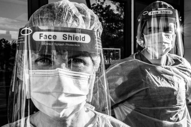 Dramatic Black and white image of Tired, overworked, exhausted health care workers outside the hospital Dramatic Black and white image of Tired, overworked, exhausted health care workers outside the hospital looking at the camera overworked photos stock pictures, royalty-free photos & images