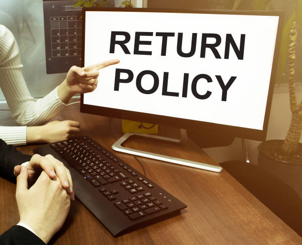 istock male and female hand, computer with text Return Policy with office background 1257460500