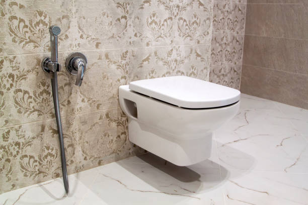 opgeschort toilet en hygiënische douche in binnenlands die met mooie tegels met bloemisch patroon en marmeren vloer wordt verfraaid - toilet hangend stockfoto's en -beelden