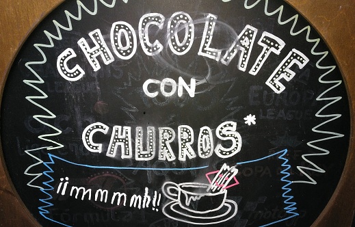 Churros and hot chocolate, handwriting sign with chalk on blackboard.
