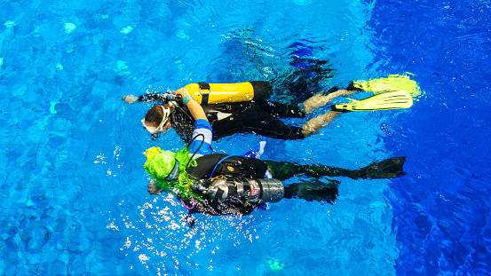Diving instructor and students. Instructor teaches students to dive in the swimming pool.