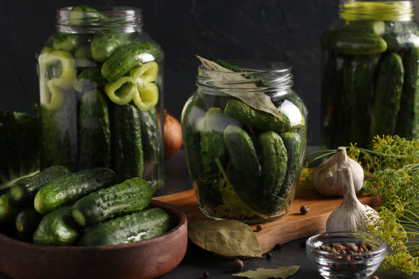 istock Marinated cucumbers with garlic, pepper and dill in a glass jars on dark background, Horizontal format 1257466689