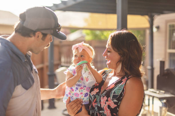 millennial eltern mit mutter halten weibliche kleinkind tochter im freien auf patio - middle class stock-fotos und bilder
