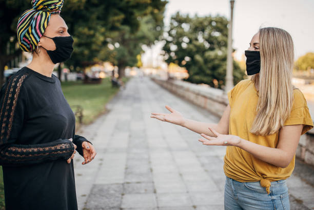 istock Two girlfriends with protective face mask talking in safe distance outdoors 1257468305