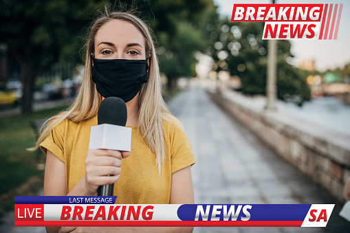 One young female reporter with protective face mask in live broadcasting relays today's breaking news.