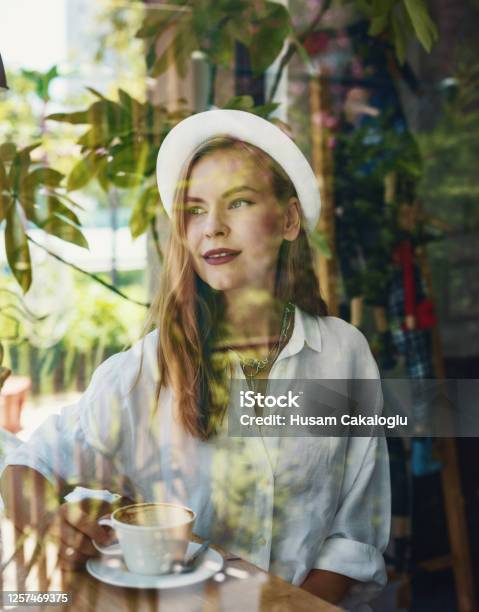 Beautiful Woman Is Resting While Drink A Cup Of Coffee In A Cafe And Watching Around Stock Photo - Download Image Now