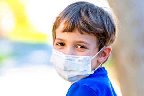 istock Little child boy at school looking at the camera using a protective face mask 1257470453