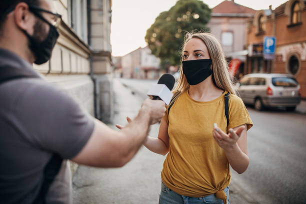 Man news reporter interviewing a woman on the street Man and woman, two people with black face masks on the street, man news reporter interviewing a woman on the street media interview photos stock pictures, royalty-free photos & images