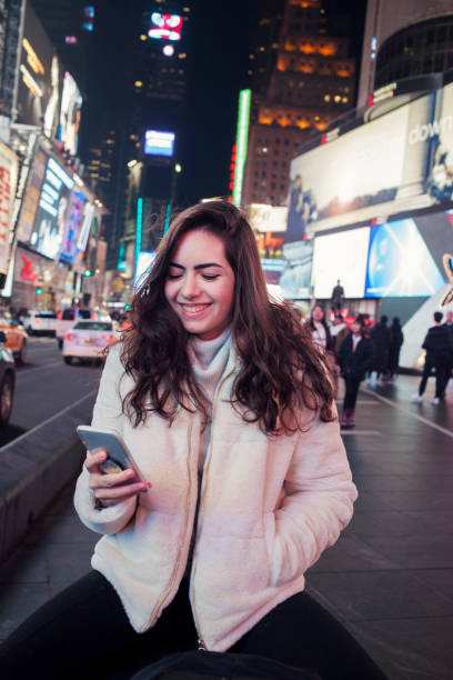 istock Happy young woman using mobile at Times Square New York 1257473208