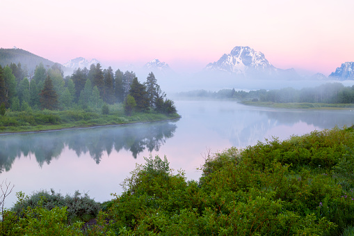 Foggy covers the Snake River at sunrise as Mt Moran extends above the fog bank in Grand Teton National Park