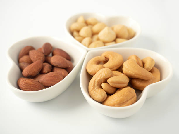 istock Nuts in Heart shaped bowls isolated on white background. Various nuts (almonds, macadamia, cashew). Mix nut for romantic feelings and healthy ingredients food. 1257487682
