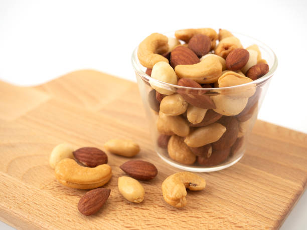 noci in ciotole di vetro a forma di cerchio su macellaio di legno isolato su sfondo bianco. varie noci (mandorle, macadamia, anacardi, arachidi). mescolare il cibo ingredienti sani di noci. - peanut bowl nut circle foto e immagini stock