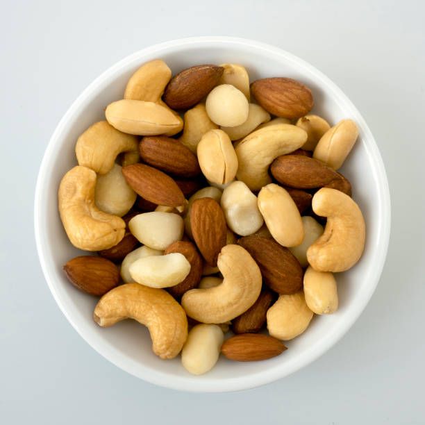 istock Nuts in top view circle shaped ceramic bowls isolated on gray background. Various nuts (almonds, macadamia, cashew, peanuts). Mix nut healthy ingredients food. 1257487697