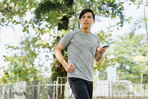 istock Young asian man jogging in a city park 1257490571
