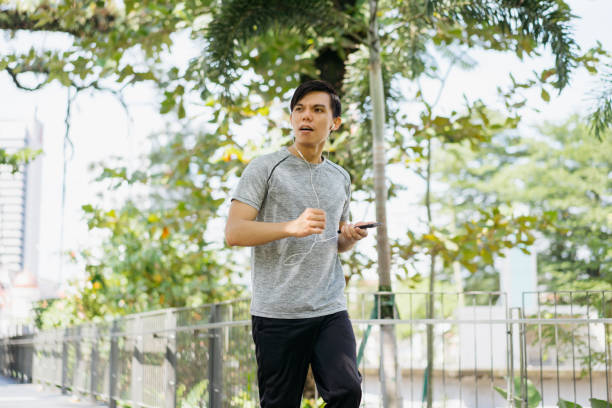 istock Young asian man jogging in a city park 1257490572