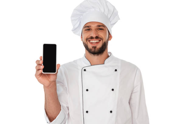 istock Smiling chef in uniform showing smartphone with blank screen isolated on white 1257500541
