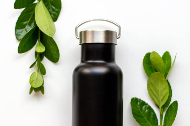 istock Black thermos with a green leaves on white background, concept reusable 1257503851