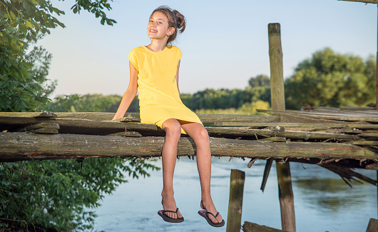 A girl sitting on a wooden bridge in the evening.