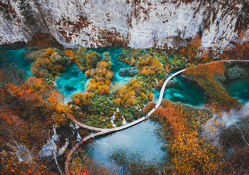 Beautiful view with wooden trekking path, autumn colors trees, lakes and waterfall landscape in Plitvice Lakes in Croatia