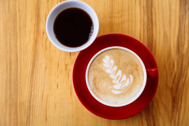 istock Coffee in a red cup with milk and latte art and coffee in a white cup on a table 1257523535
