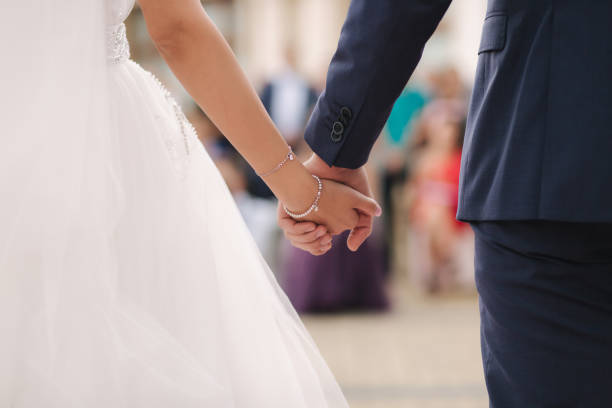 nahaufnahme des bräutigams halten braut hand vor den gästen. hochzeitszeremonie. rückansicht - bride caucasian wedding ceremony close up stock-fotos und bilder